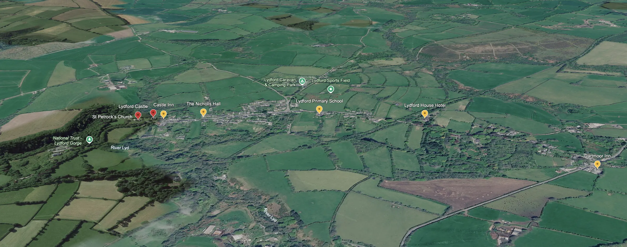 Aerial view of Lydford village on the edge of Dartmoor, showing Lydford Castle, St Petrocks Church, Lydford Gorge, the Castle Inn, the Nicholls Hall, the primary school, the sports field, the caravan and camping park, Lydford House Hotel and the Dartmoor Inn